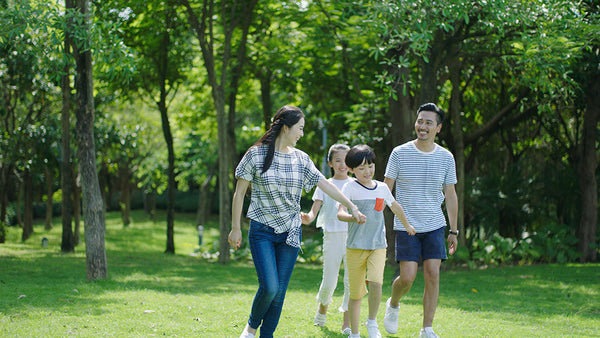 Parent and child walking through a green Singapore park during dengue season.